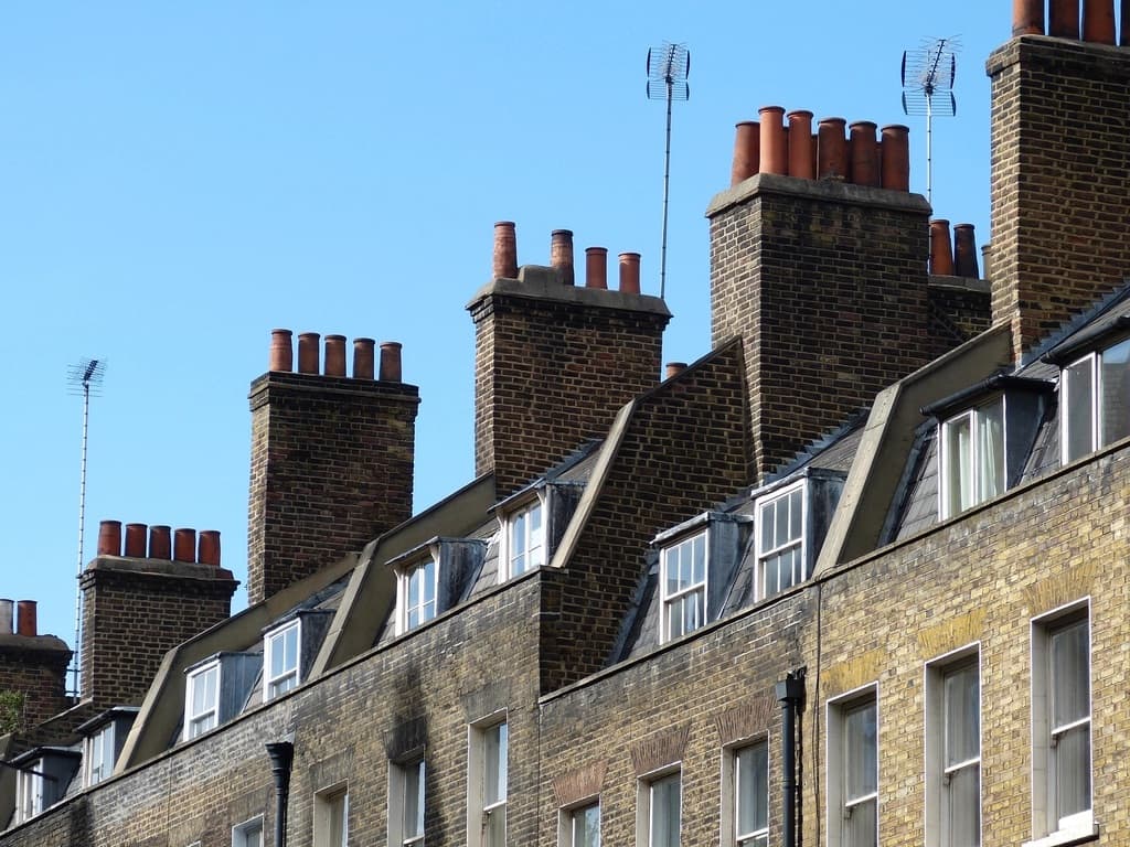 Souches de cheminées en brique et toiture d’ardoise sous un ciel bleu