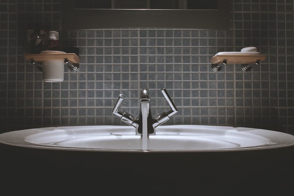 Robinet chromé avec eau qui coule sur une vasque sombre