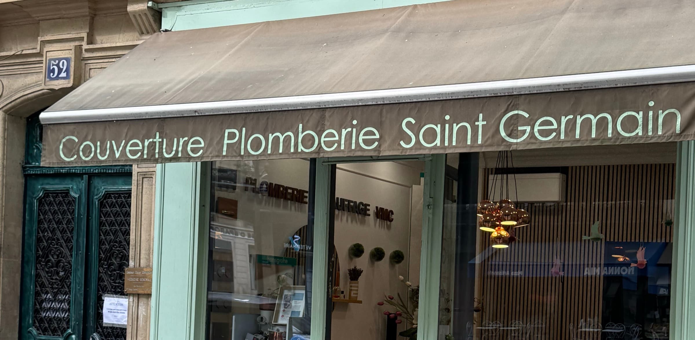 La devanture vert d’eau de Couverture Plomberie Saint Germain, 52 boulevard Saint-Germain, avec son store banne