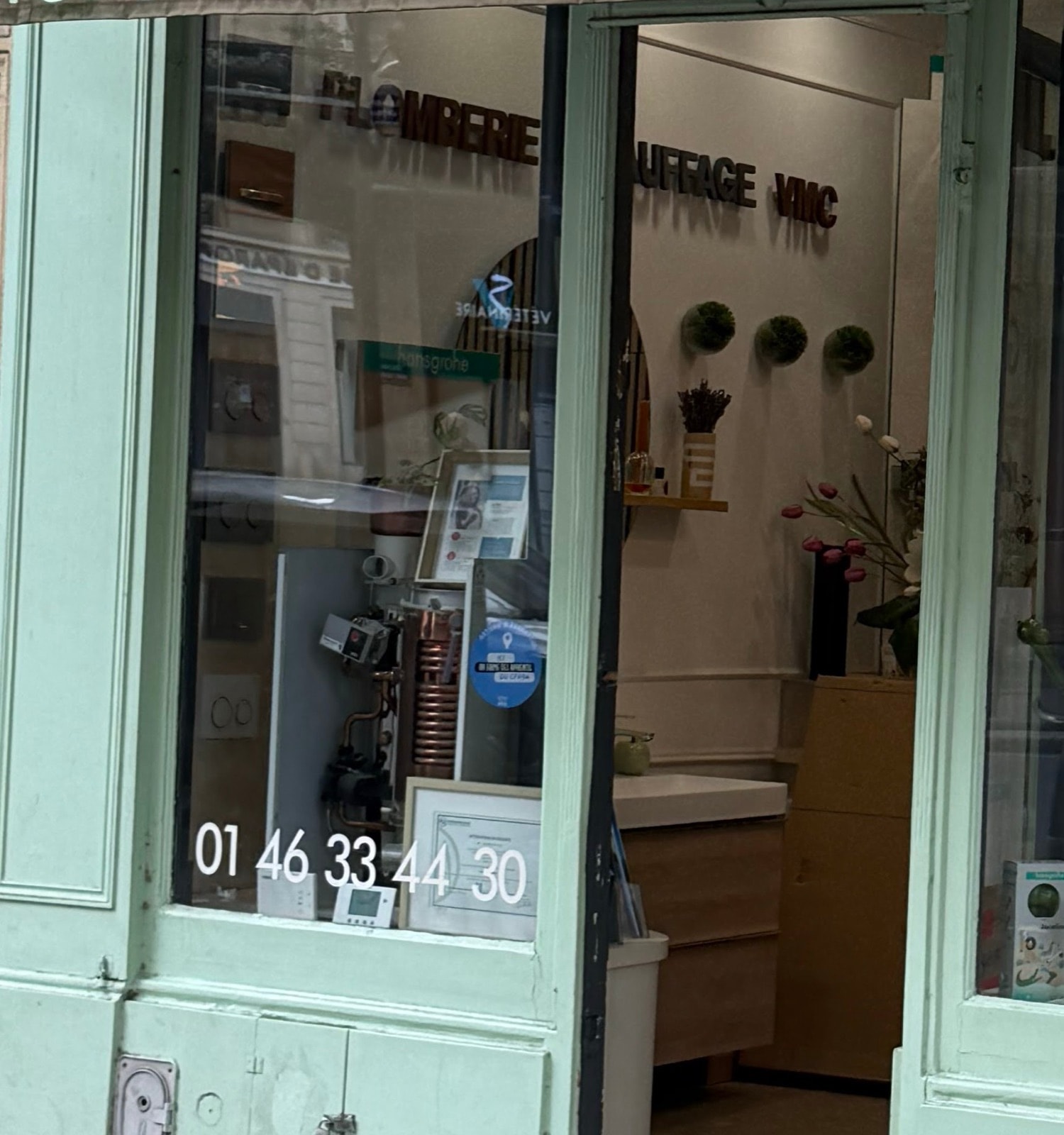 La vitrine de la boutique : numéro de téléphone, chauffe-eau cuivre en exposition et panneau Plomberie Chauffage VMC